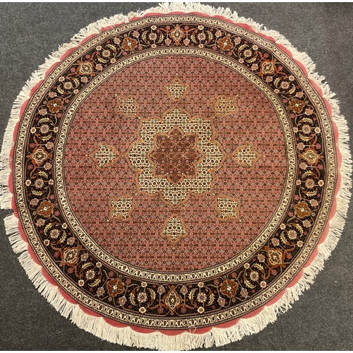 90A - A Persian circular wool and silk rug, the central floral form medallion, enclosed within a stylized ... 