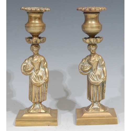 25 - A pair of Regency bronze figural candlesticks, each cast as a young lady gathering flowers, spreadin... 