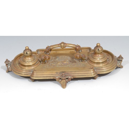 34 - A Victorian brass inkstand, in the Renaissance Revival taste, central arched handle terminating in g... 