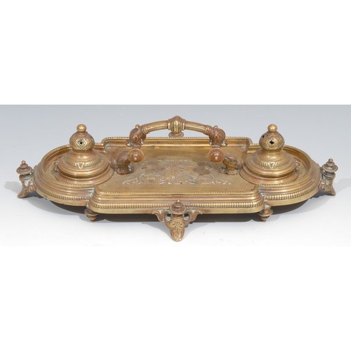 34 - A Victorian brass inkstand, in the Renaissance Revival taste, central arched handle terminating in g... 