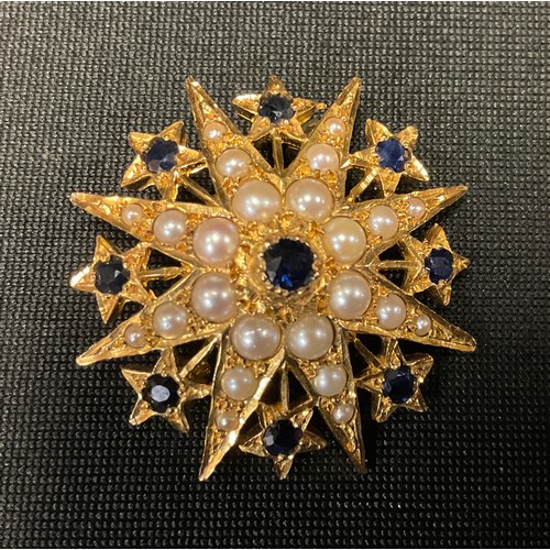 745A - A 9ct gold star shaped brooch, set with graduate seed pearls, divided and centred with sapphires