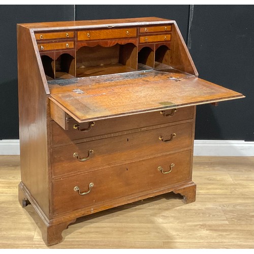 118 - A George III oak bureau, fall front enclosing small drawers and pigeonholes, above four long graduat... 