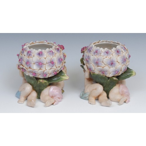 166 - A pair of Continental porcelain vases, each modelled with flowers supported by scantily clad putti, ... 