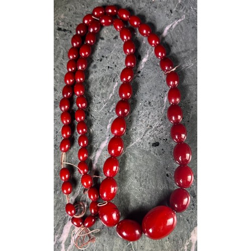 1021 - A 'Cherry Amber' type graduated bead necklace, 61 oval beads, approximately 41cm drop, 62g gross