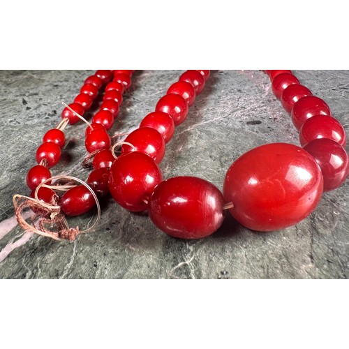 1021 - A 'Cherry Amber' type graduated bead necklace, 61 oval beads, approximately 41cm drop, 62g gross