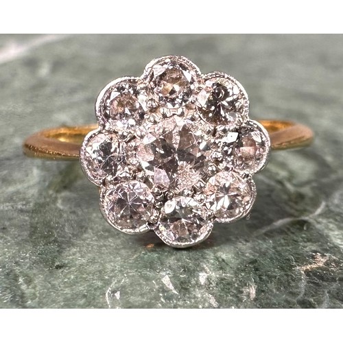 1004 - An 18ct gold and diamond flowerhead ring, the central stone flanked by 8 further smaller stones, app... 