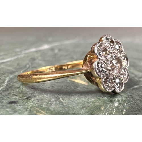 1004 - An 18ct gold and diamond flowerhead ring, the central stone flanked by 8 further smaller stones, app... 