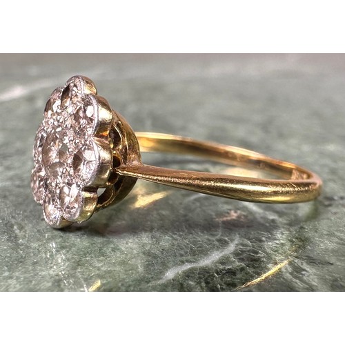 1004 - An 18ct gold and diamond flowerhead ring, the central stone flanked by 8 further smaller stones, app... 