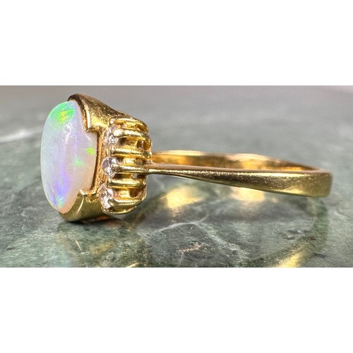 1027 - An opal and diamond ring, central oval cabochon opal flashing vibrant blue green play, between three... 