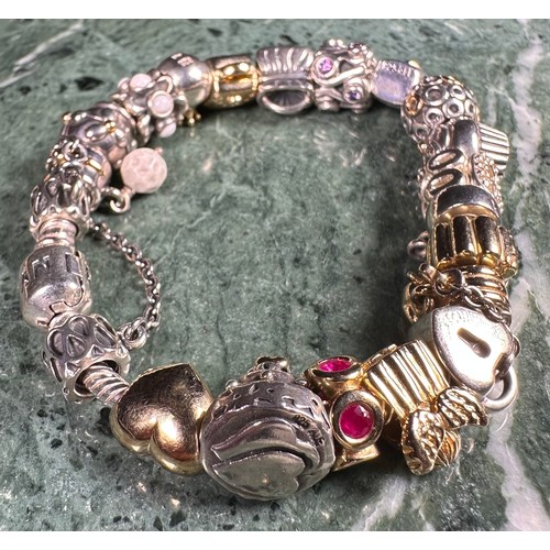 1036 - A silver Pandora moments snake chain charm bracelet, threaded with 20 14ct gold and silver charm bea... 