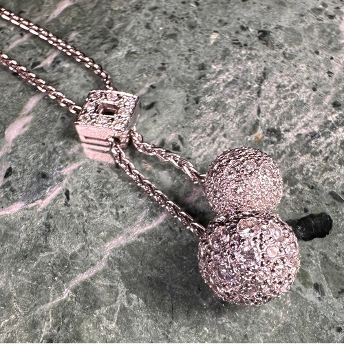 1014 - An 18ct white gold and diamond pendant necklace, the two spheres set with round brilliant cut stones... 