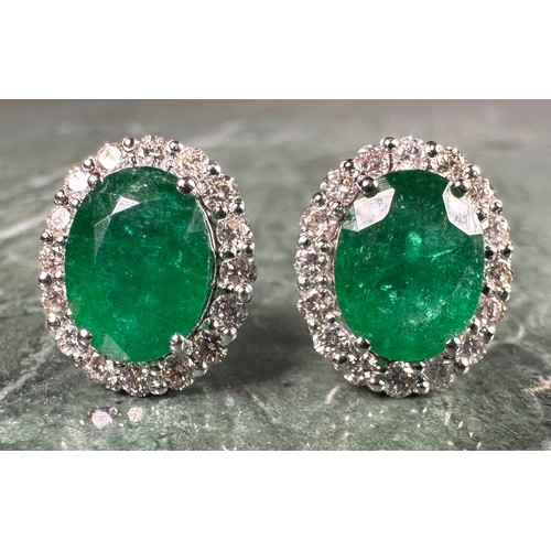 976 - A pair of emerald and diamond oval cluster earrings, each with a central oval emerald, approx 1.38ct... 