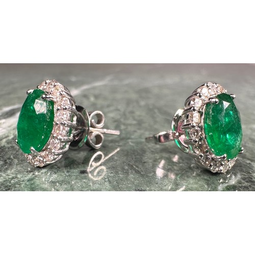 976 - A pair of emerald and diamond oval cluster earrings, each with a central oval emerald, approx 1.38ct... 