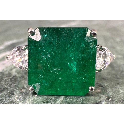 1025 - An Emerald and diamond ring, central square emerald cut emerald, approx 6.05ct mounted between pear ... 