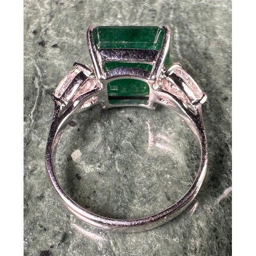 1025 - An Emerald and diamond ring, central square emerald cut emerald, approx 6.05ct mounted between pear ... 