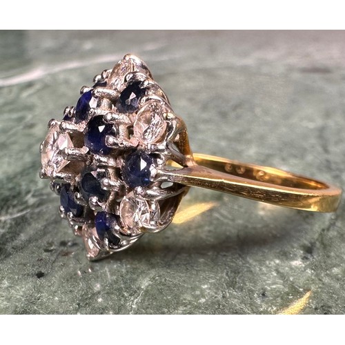 1006 - An 18ct gold diamond and sapphire flowerhead cluster ring, the central brilliant cut diamond flanked... 