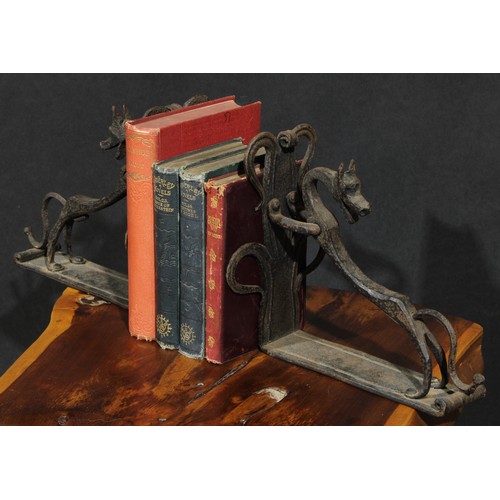 1161 - A pair of Arts and Crafts wrought iron book ends, each worked with a stylised dog, the uprights with... 