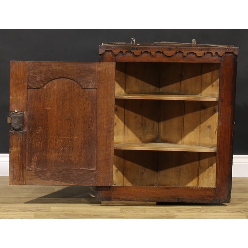 2087 - An 18th century oak wall-hanging corner cupboard, of unusual proportions, applied shaped cut-card fr... 