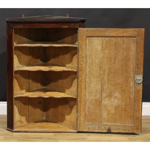 2087 - An 18th century oak wall-hanging corner cupboard, of unusual proportions, applied shaped cut-card fr... 