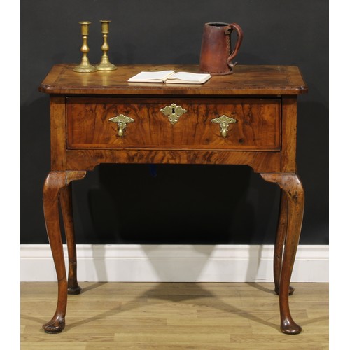 1589 - A George I walnut lowboy, quarter-veneered crossbanded top with reentrant angles, above a long friez... 