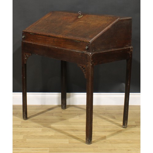 2125 - A George III provincial oak desk on stand, fall front enclosing an arrangement of pigeonholes, mould... 