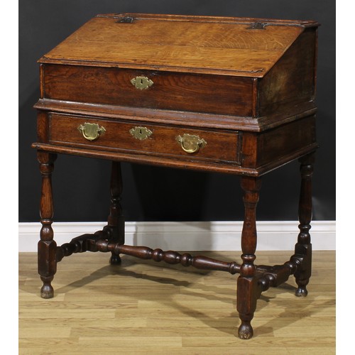 2145 - An early 18th century oak desk box on stand, hinged top enclosing pigeonholes, the base with a long ... 