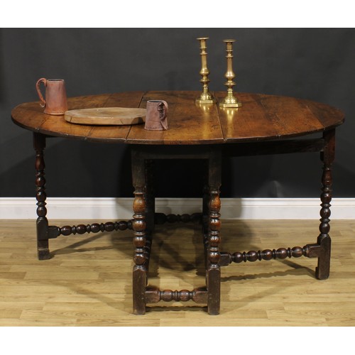 2146 - An 18th century oak gateleg dining table, oval top with fall leaves, bead and reel turned supports a... 