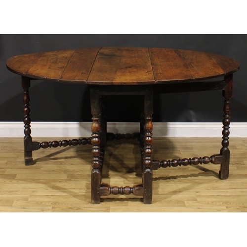 2146 - An 18th century oak gateleg dining table, oval top with fall leaves, bead and reel turned supports a... 