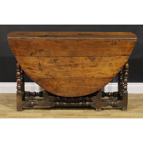 2146 - An 18th century oak gateleg dining table, oval top with fall leaves, bead and reel turned supports a... 