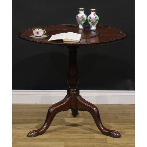 2108 - A George III Revival mahogany tripod supper table, shaped circular tilting top, carved with borders ... 