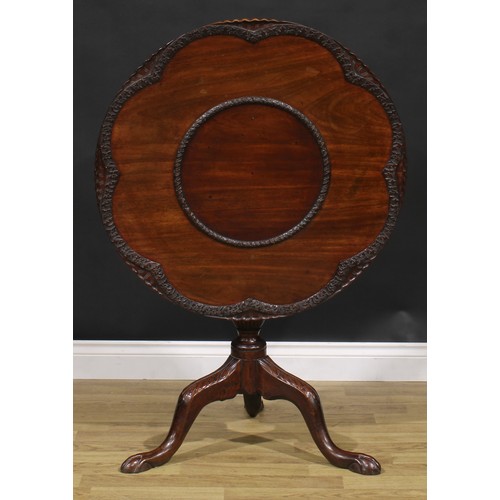 2108 - A George III Revival mahogany tripod supper table, shaped circular tilting top, carved with borders ... 