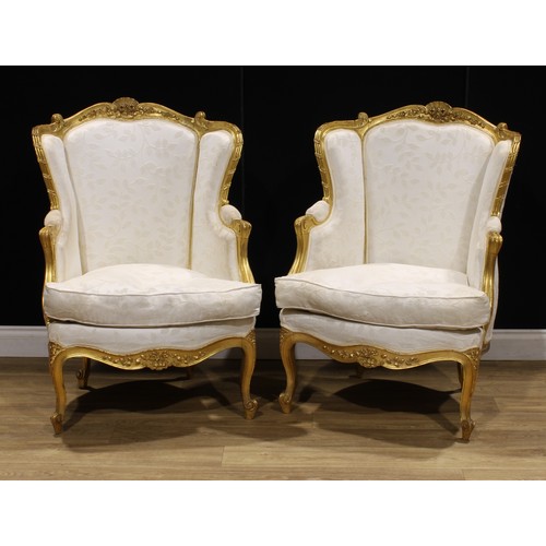 1601 - A pair of Louis XV Revival giltwood bergère cabriolet, stuffed-over upholstery, squab cushion, 101.5... 