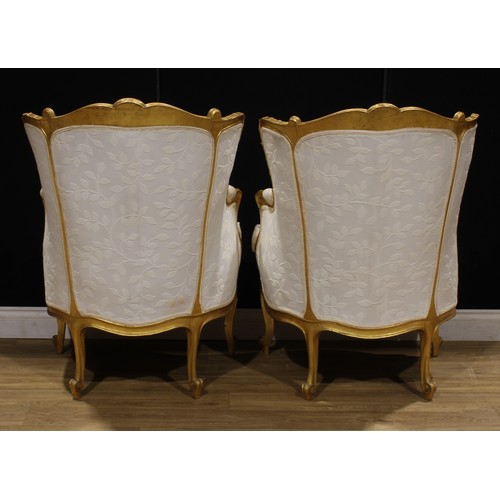 1601 - A pair of Louis XV Revival giltwood bergère cabriolet, stuffed-over upholstery, squab cushion, 101.5... 