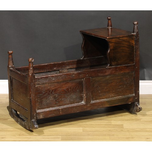 2078 - An 18th century oak rocking crib, rectangular canopy with shaped supports, turned finials, panelled ... 