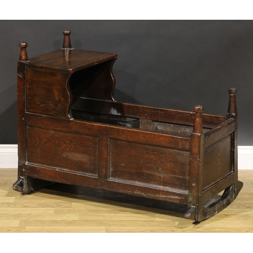 2078 - An 18th century oak rocking crib, rectangular canopy with shaped supports, turned finials, panelled ... 