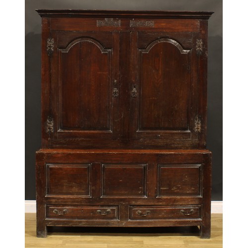 2115 - An 18th century oak bacon press or housekeeper’s cupboard, outswept cornice above a pair of arched r... 