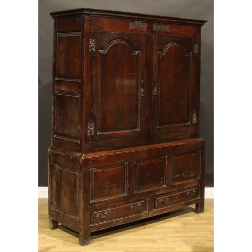 2115 - An 18th century oak bacon press or housekeeper’s cupboard, outswept cornice above a pair of arched r... 