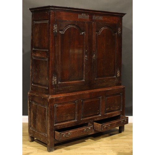 2115 - An 18th century oak bacon press or housekeeper’s cupboard, outswept cornice above a pair of arched r... 