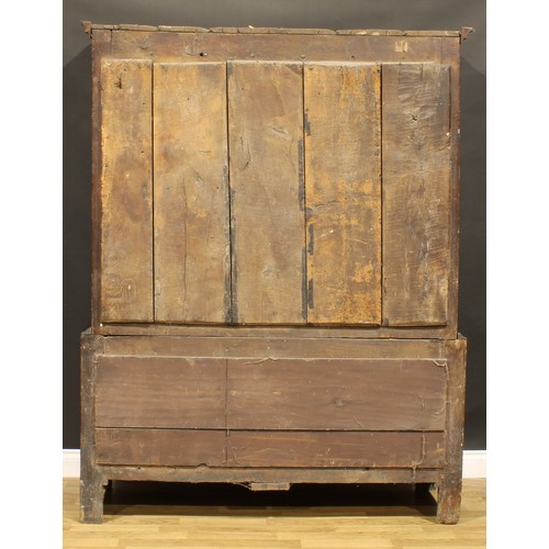 2115 - An 18th century oak bacon press or housekeeper’s cupboard, outswept cornice above a pair of arched r... 