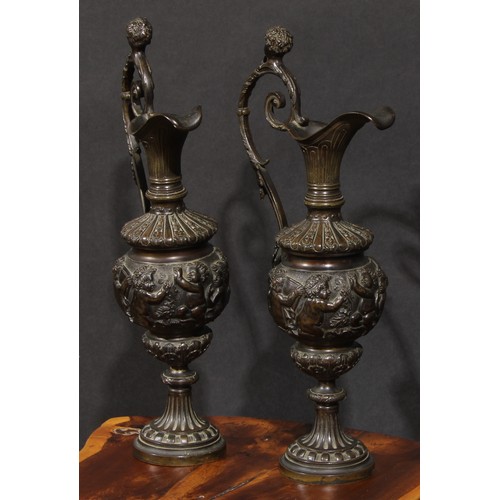 2136 - A pair of 19th century brown patinated bronze ewers, cast in the Grand Tour taste with bands of putt... 