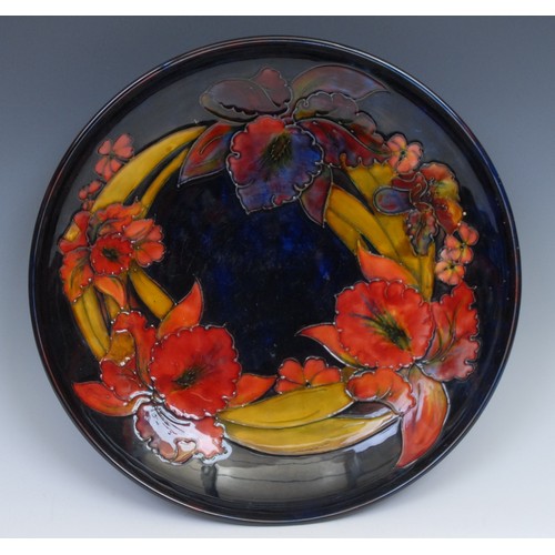 10 - A Moorcroft Iris pattern charger, tube lined on a mottled blue ground, 31.5cm diameter, impressed ma... 