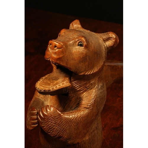 1090 - Nutcrackers - a Black Forest novelty lever-action nut cracker, carved as a bear, standing, hungry fo... 