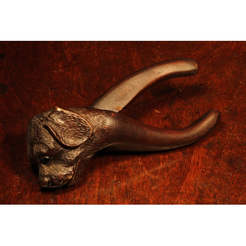 1096 - Nutcrackers - a Black Forest novelty lever-action nut cracker, carved as the head of a dog, glass ey... 