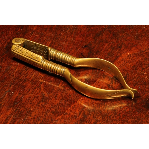 1141 - Nutcrackers - an early 18th century brass lever-action nut cracker, 11cm long, marked *J, c.1720