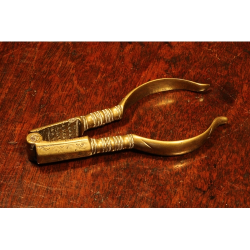 1142 - Nutcrackers - an early 18th century brass lever-action nut cracker, decorated with wrigglework, 11cm... 