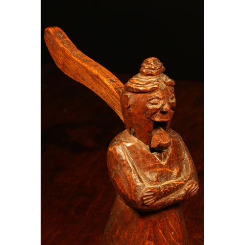 1158 - Nutcrackers - an early 20th century oak folk art table top nut cracker, naively carved as a figure s... 