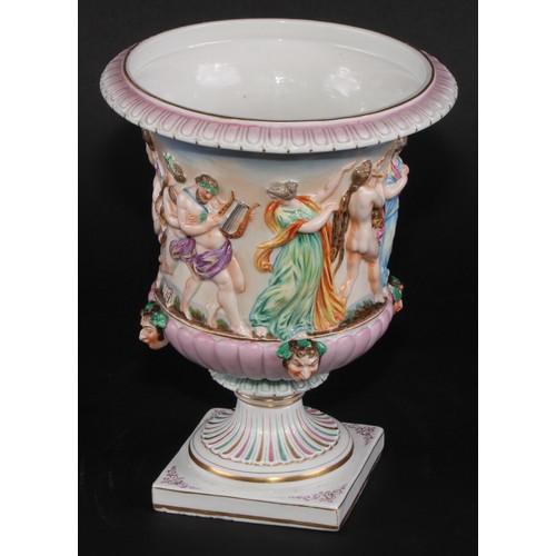 150 - A Naples porcelain campana shaped mantel urn, moulded in relief with classical figures dancing and p... 