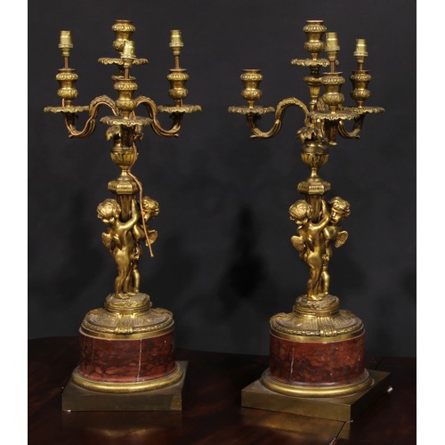 2162 - A pair of French gilt bronze figural five light candelabra, the pillars cast with putti, marble socl... 