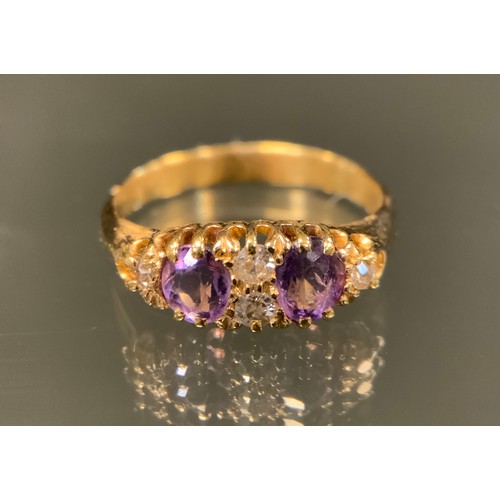 455 - A late 19th /early 20th century diamond and amethyst ring, two pale purple amethysts divided by a pa... 