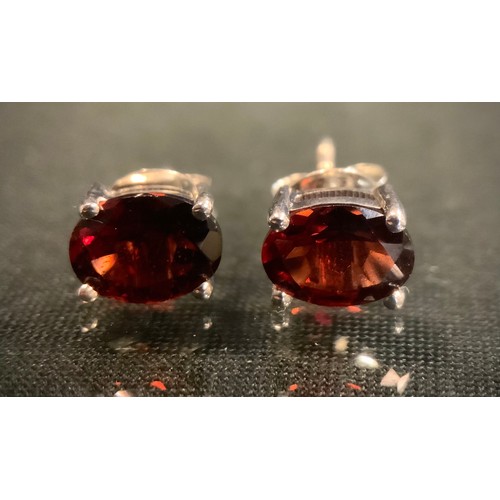 475 - A pair of oval red garnet stud earrings, silver mounts, 1.9g gross.